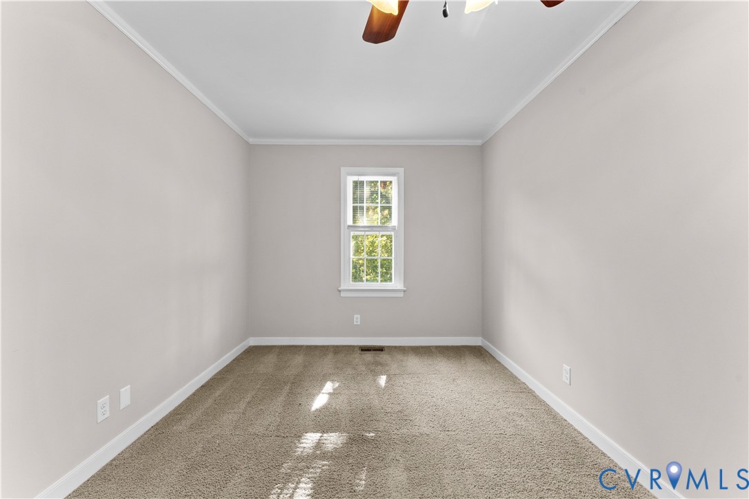 Neutral-toned room featuring neutral carpeting, a single double-hung window, and a ceiling fan with light fixture