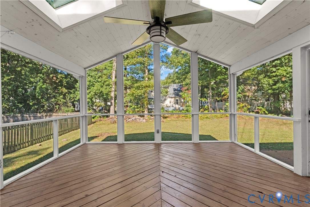 Screened porch with vaulted ceiling, wood-plank flooring laid in a chevron pattern, dual skylights, and a central ceiling fan