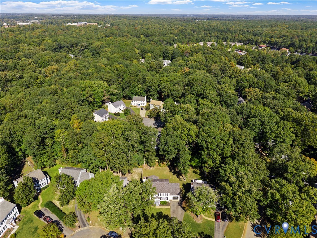 Aerial perspective featuring a low-density residential setting surrounded by mature, densely wooded foliage