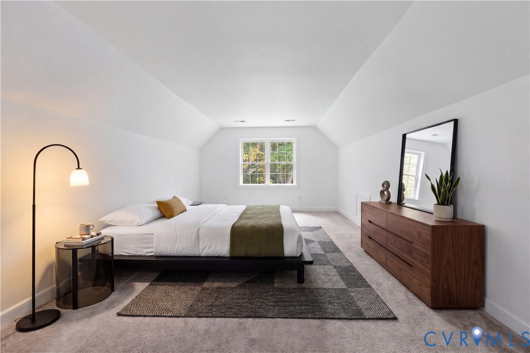Vaulted ceiling featuring neutral wall-to-wall carpeting and a centered multi-pane window