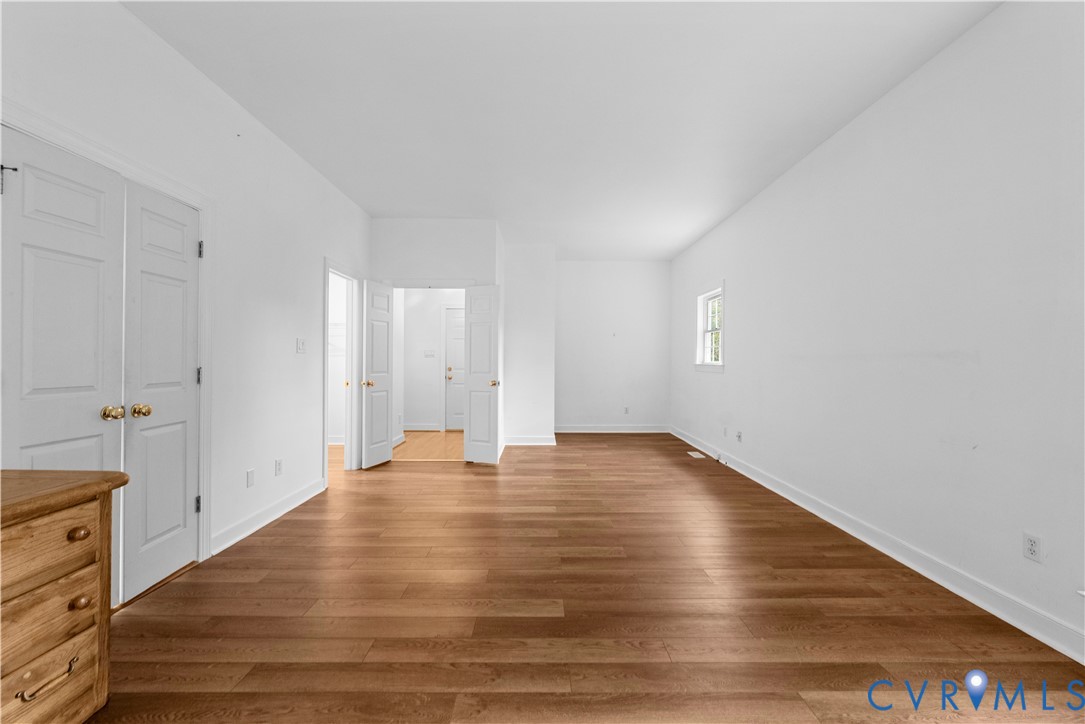 Neutral interior space featuring wood-finish flooring, white walls, and multi-panel interior doors