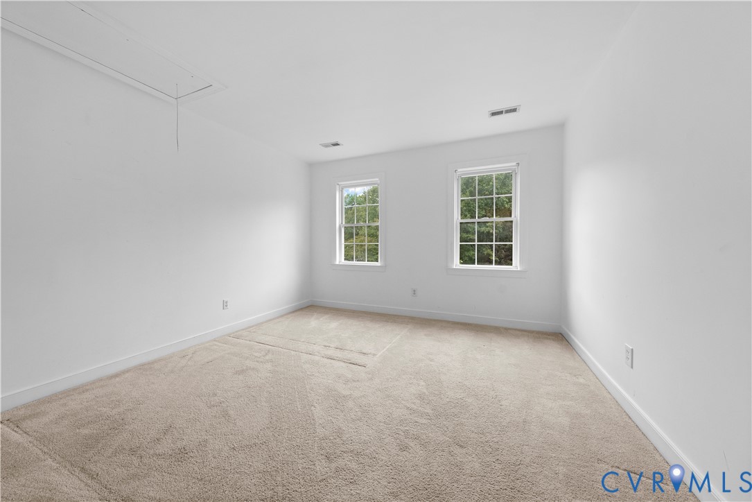 Neutral interior space featuring wall-to-wall carpeting, two multi-pane windows, and an integrated ceiling access panel
