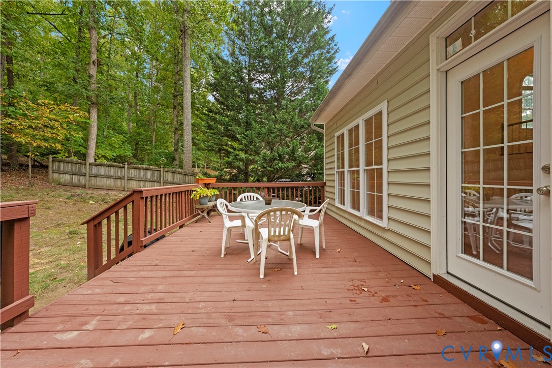 Elevated wooden deck with balustrade, horizontal siding exterior, and multi-light glass door