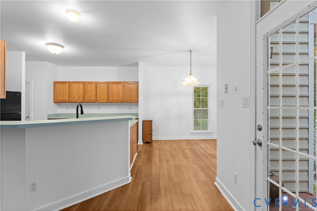 Kitchen area featuring wood-finish flooring, wood cabinetry, a peninsula with a solid-surface countertop, and a glass-paneled exterior door