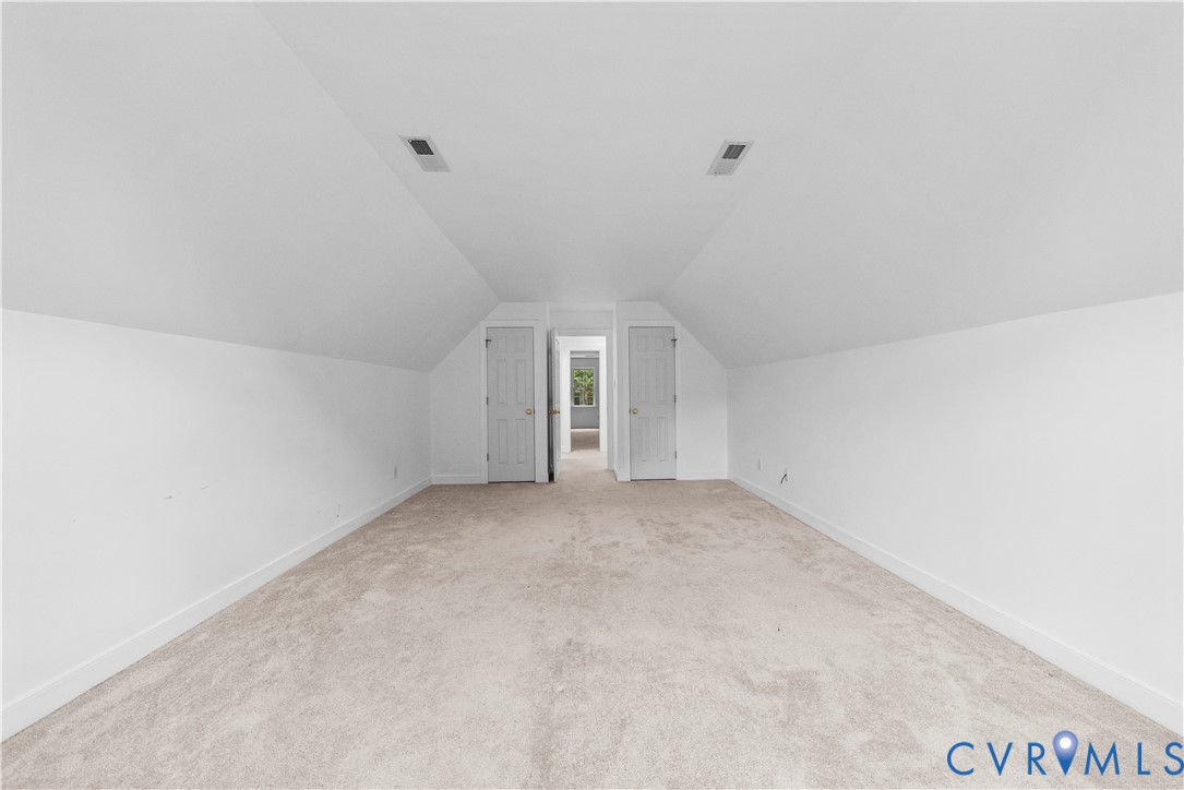 Sloped ceiling architecture featuring wall-to-wall carpeting and dual interior doors