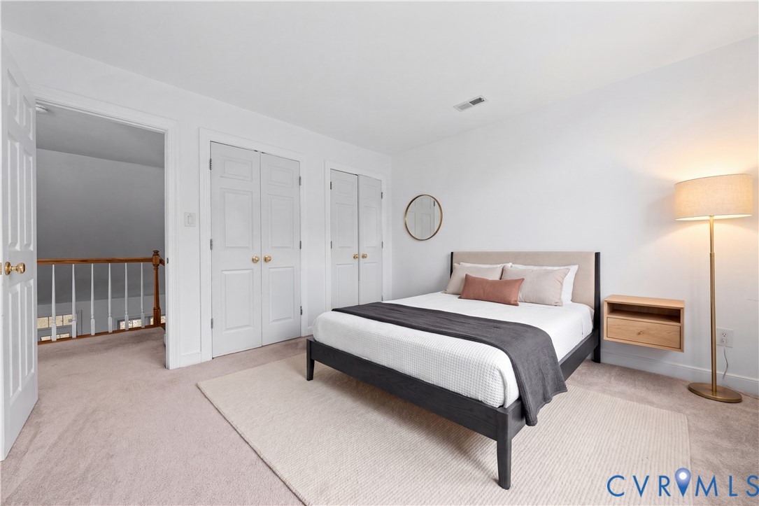 Neutral-toned carpeting, dual paneled-door closets, and a wall-mounted floating wood shelf