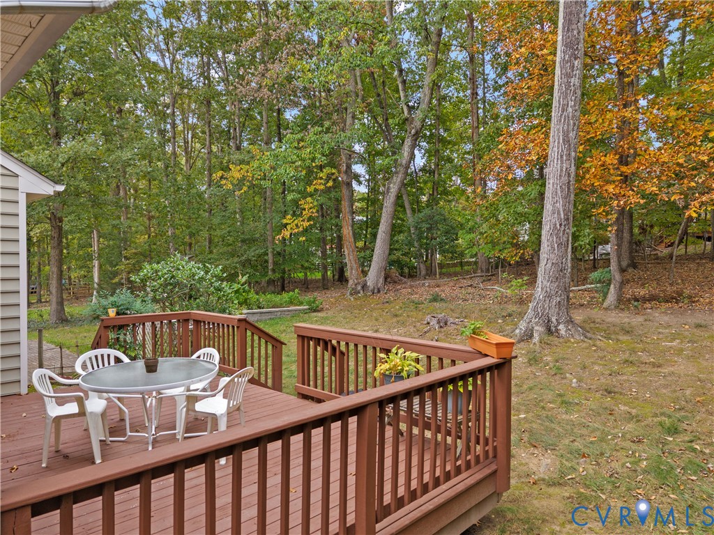 Raised wood deck featuring vertical balusters and a sloped backyard area with mature trees