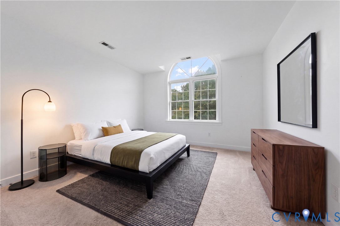 Neutral-toned interior featuring an arched window with grid mullions and wall-to-wall carpeting