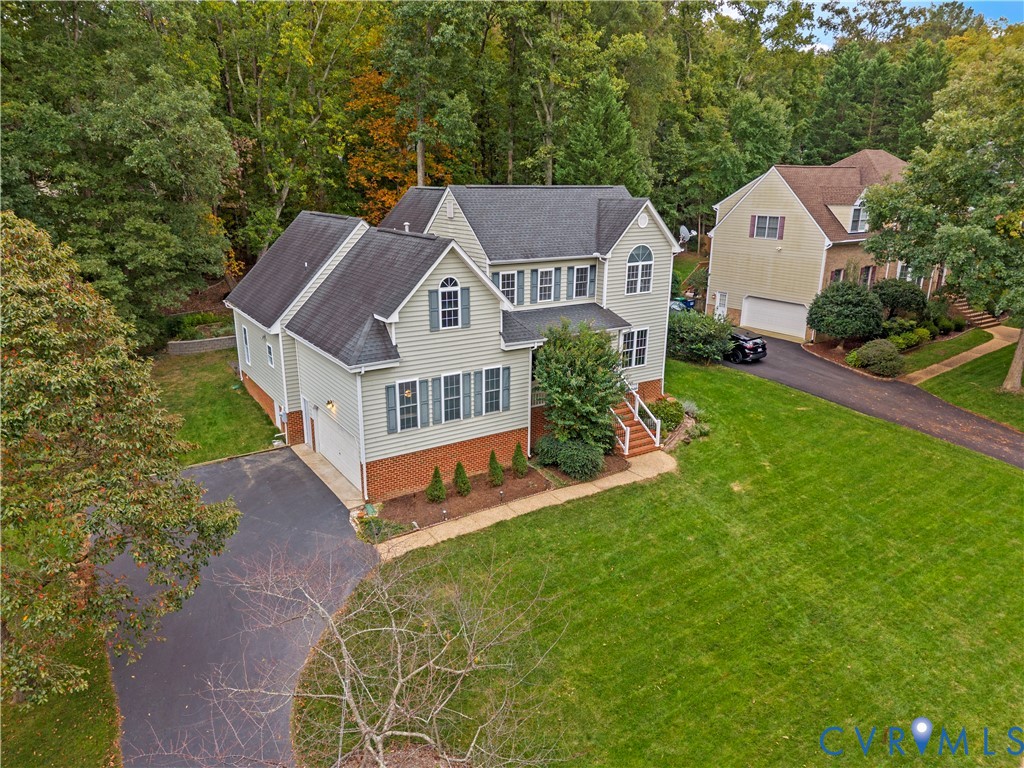 Multi-level residence featuring a brick and vinyl siding exterior, asphalt shingle roof, expansive manicured lawn, and attached garage