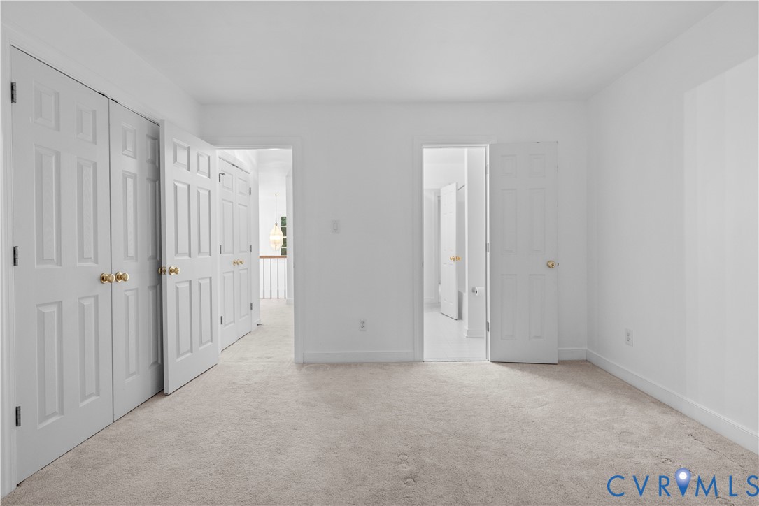 Neutral-toned carpeted flooring, multi-panel doors with metallic hardware, and white interior paint