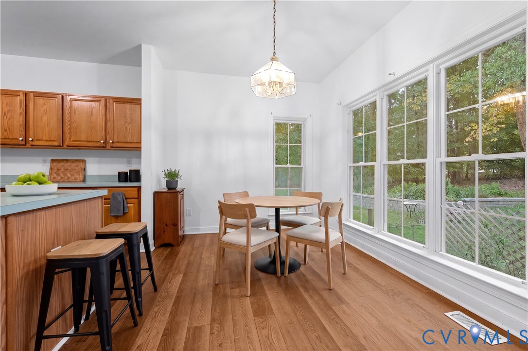 Wood-finish flooring, natural wood cabinetry, pendant lighting, and oversized multi-pane windows