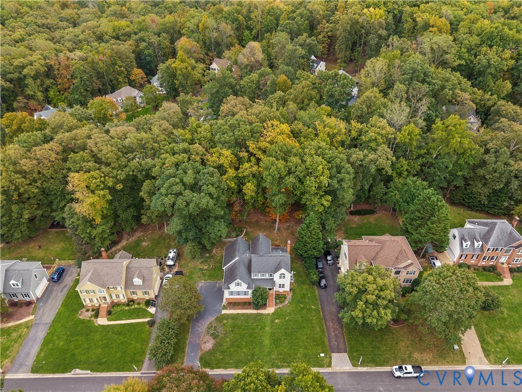 Aerial perspective of residential properties featuring expansive tree-lined lots and paved driveways