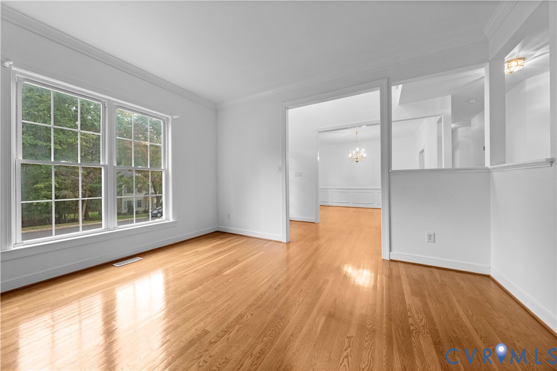Interior space featuring wood-finish flooring, multi-pane windows, crown molding, and wainscoting