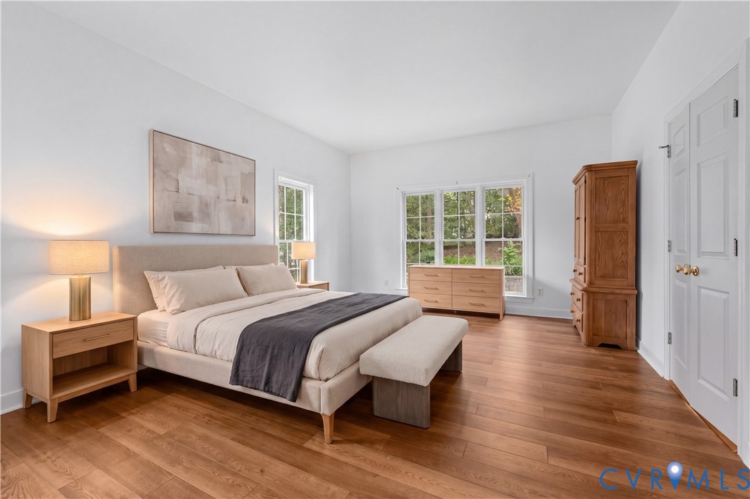 Spacious room featuring wood-finish flooring, crisp white walls, and oversized windows with multi-pane grids