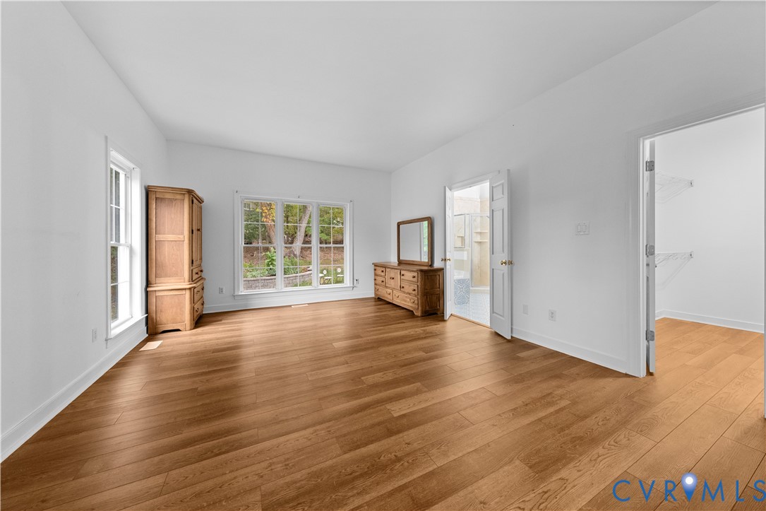 Room featuring wood-finish flooring, multi-pane windows, double doors, and a reach-in closet with wire shelving