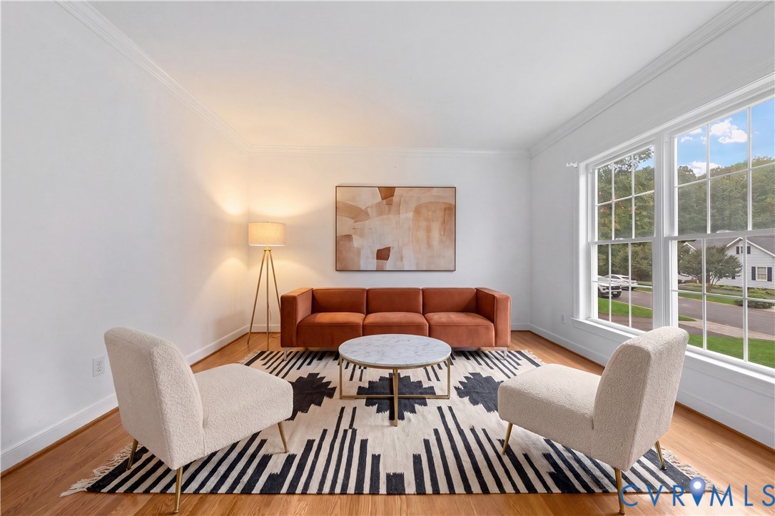 Room featuring wood-finish flooring, crown molding, and large divided-light windows
