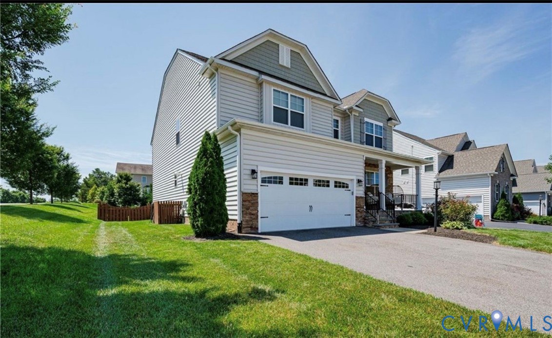 Two-story residence featuring siding and stone accents, a covered front porch, and an attached two-car garage