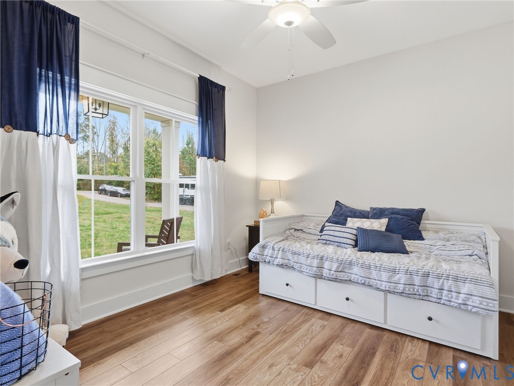 Room featuring wood-finish flooring, a large multi-pane window, and a ceiling fan with integrated lighting