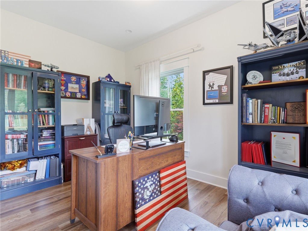 Room featuring wood-finish flooring, dual built-in navy cabinetry with glass-panel doors, and a double-hung window with natural light