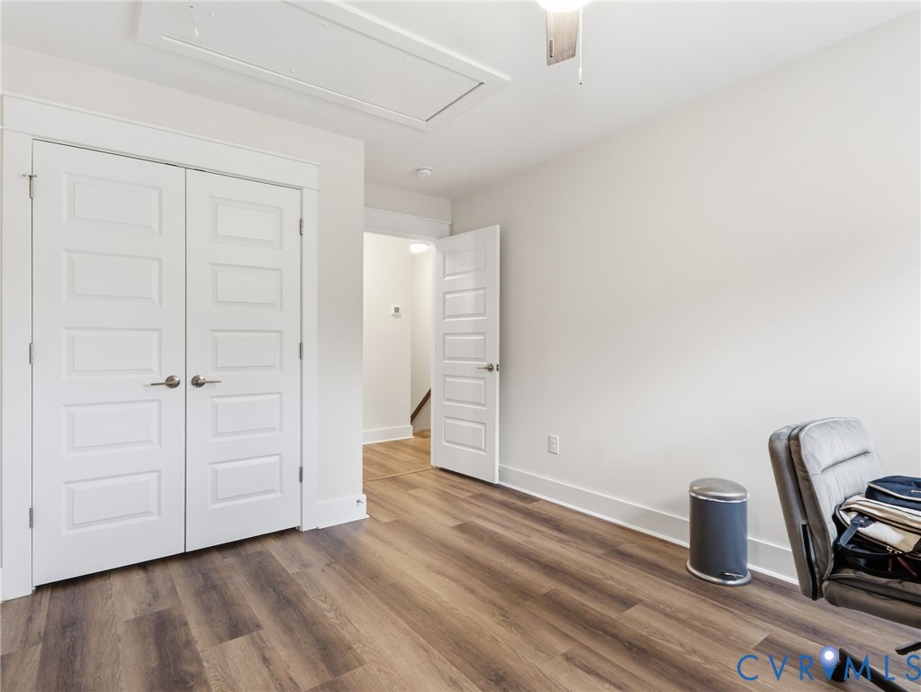 Interior space featuring wood-finish flooring, double-panel closet doors with satin nickel hardware, and a five-panel interior door
