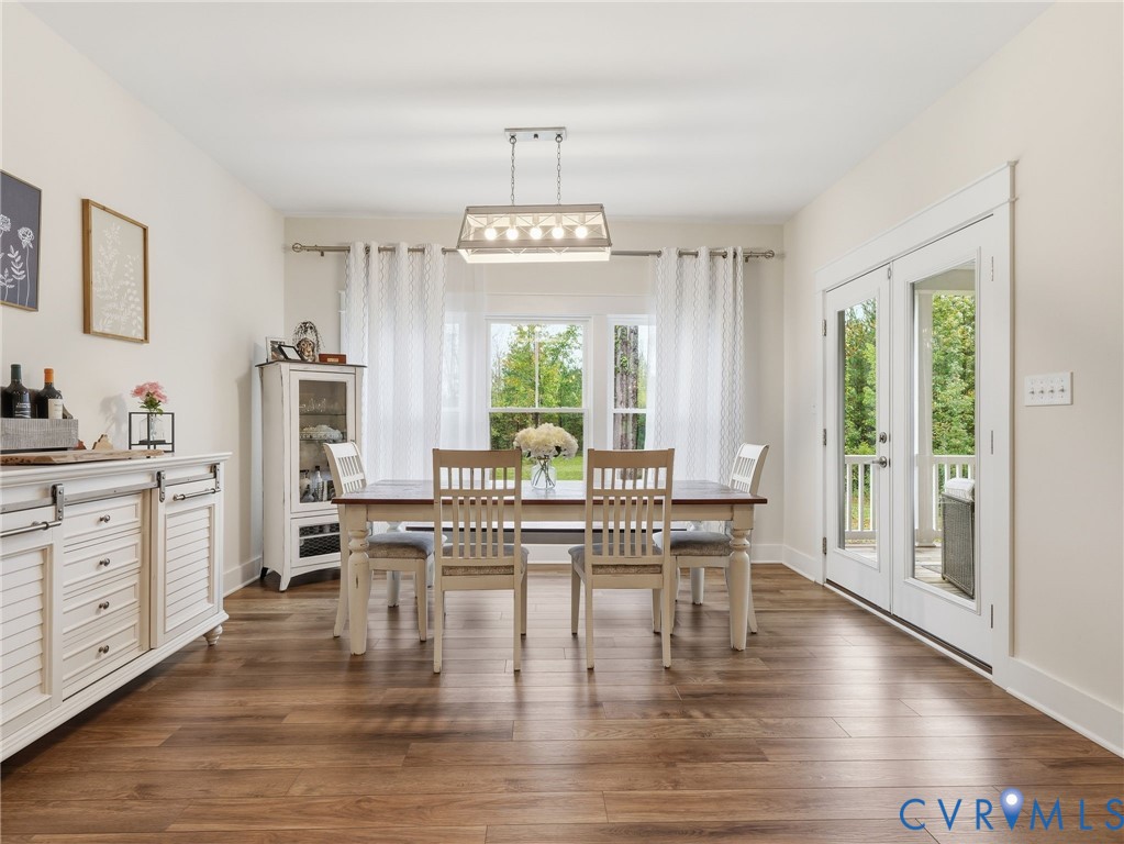 Dining area featuring wood-finish flooring, a rectangular multi-light pendant fixture, double glass-panel doors, and crisp white millwork casing