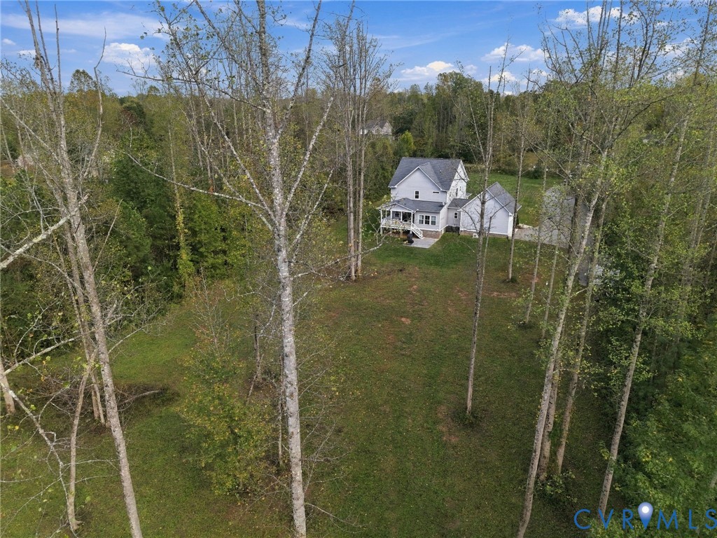 Spacious lot featuring established trees, a covered rear porch, and a paved concrete patio