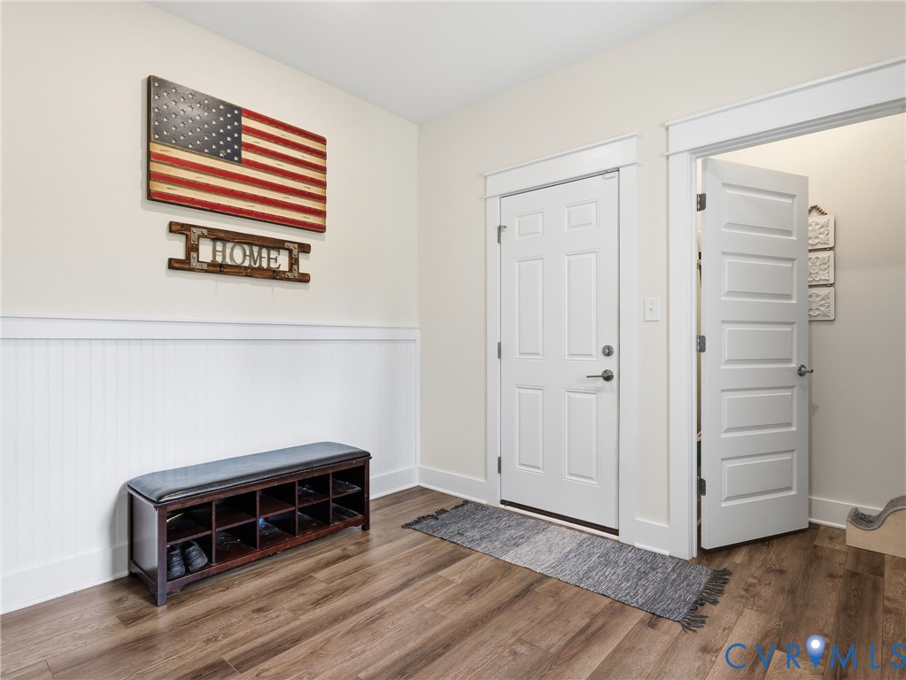 Entryway featuring wood-finish flooring, white beadboard wainscoting, and white six-panel interior doors