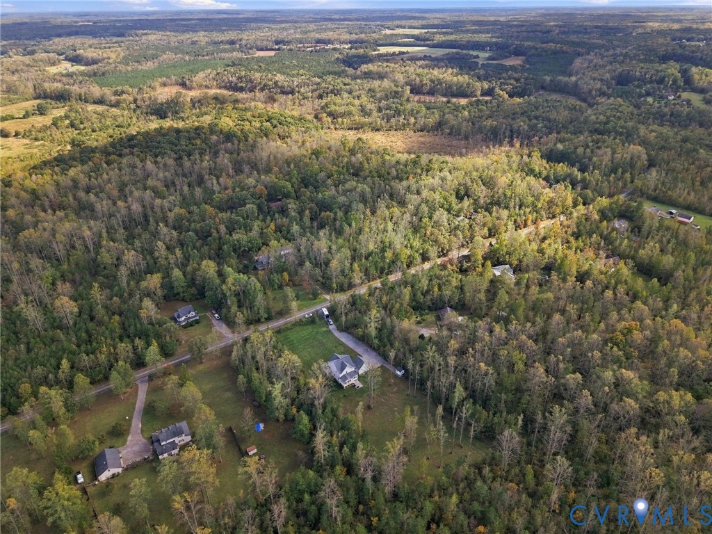 Aerial perspective of a multi-acre property featuring expansive wooded terrain and manicured lawn space