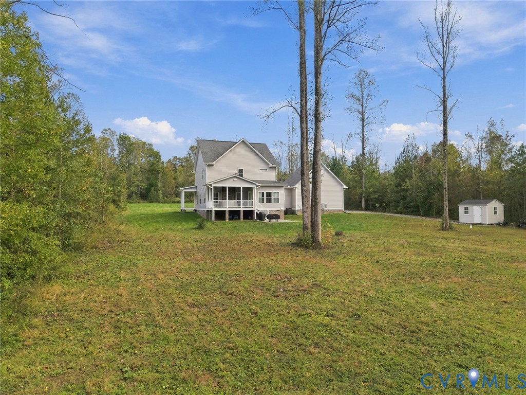 Two-story residence featuring a screened rear porch, elevated deck, expansive yard, and a detached storage structure