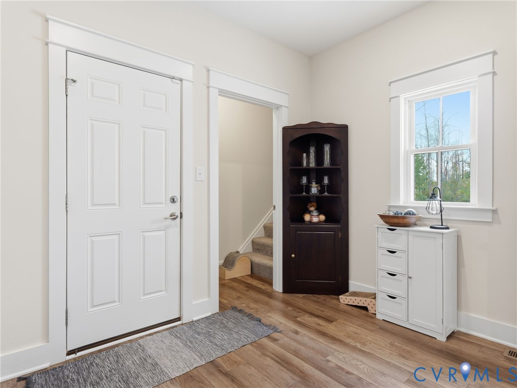 Entryway featuring wood-finish flooring, a six-panel door, and window trim with classic casing