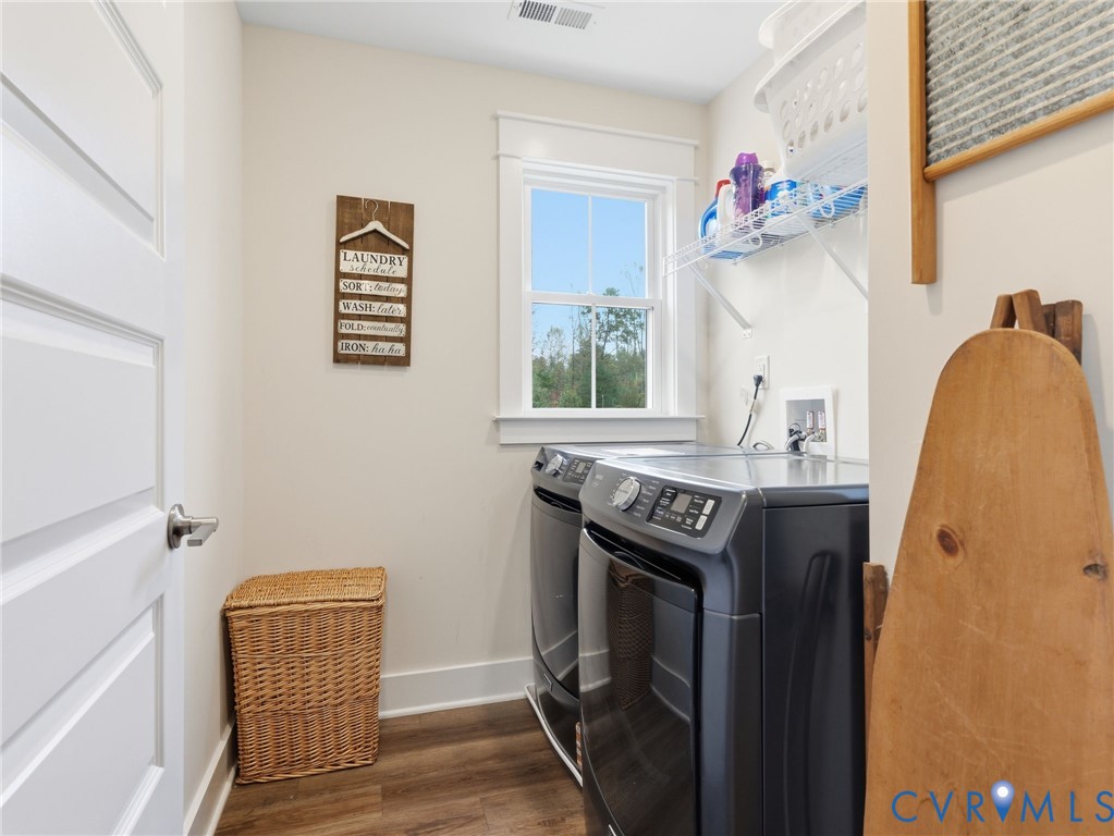 Laundry room featuring wood-finish flooring, a double-hung window with casing, and a white interior door with a brushed nickel lever handle