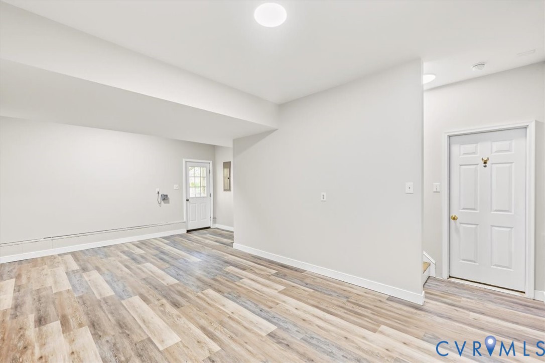 Neutral color palette featuring wood-finish flooring, recessed lighting, and a six-panel interior door