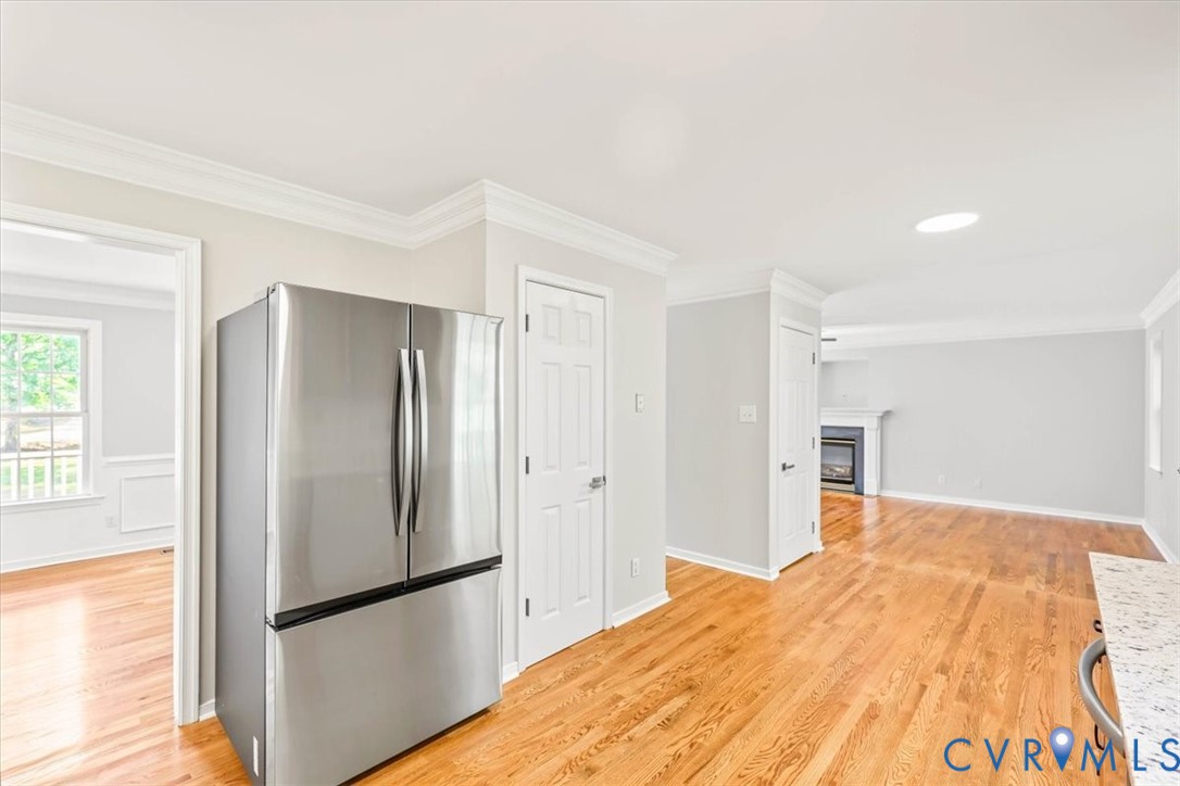 Stainless steel French door refrigerator, wood-finish flooring, crown molding, and recessed lighting