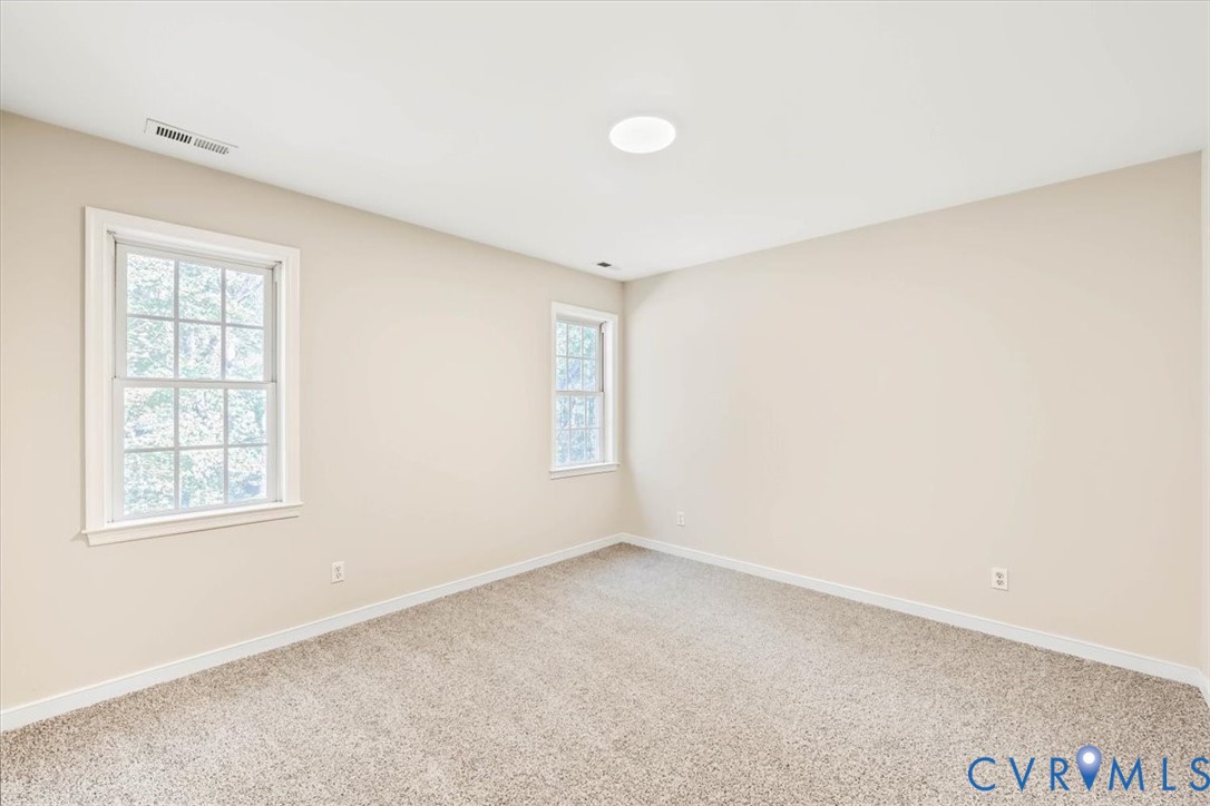 Neutral-toned walls, wall-to-wall carpeting, and double-hung windows with white casing