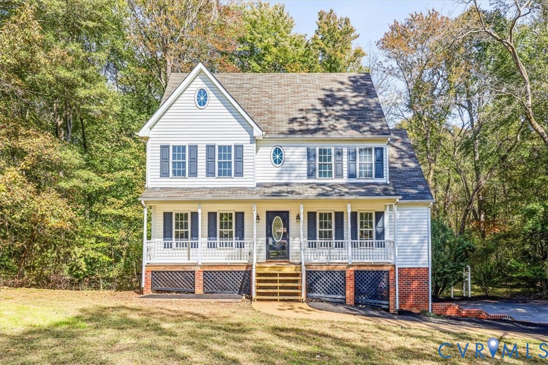 Two-story colonial exterior featuring white lap siding, dark shutter accents, an elevated front porch with white railing, and decorative oval windows