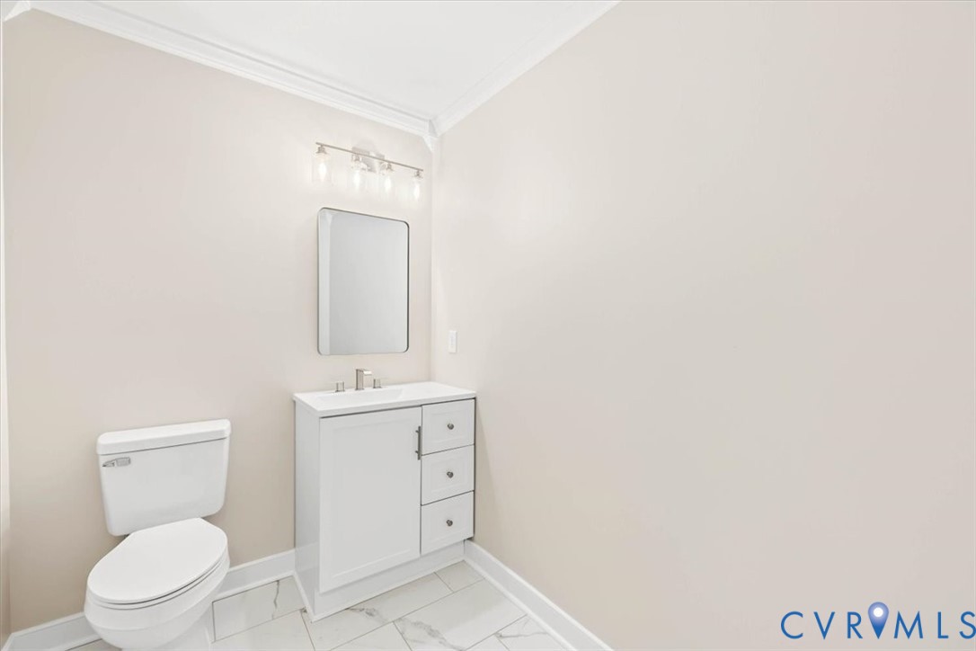 White vanity with integrated basin and cabinet storage, rectangular wall-mounted mirror, multi-bulb vanity light, and stone-finish tile flooring