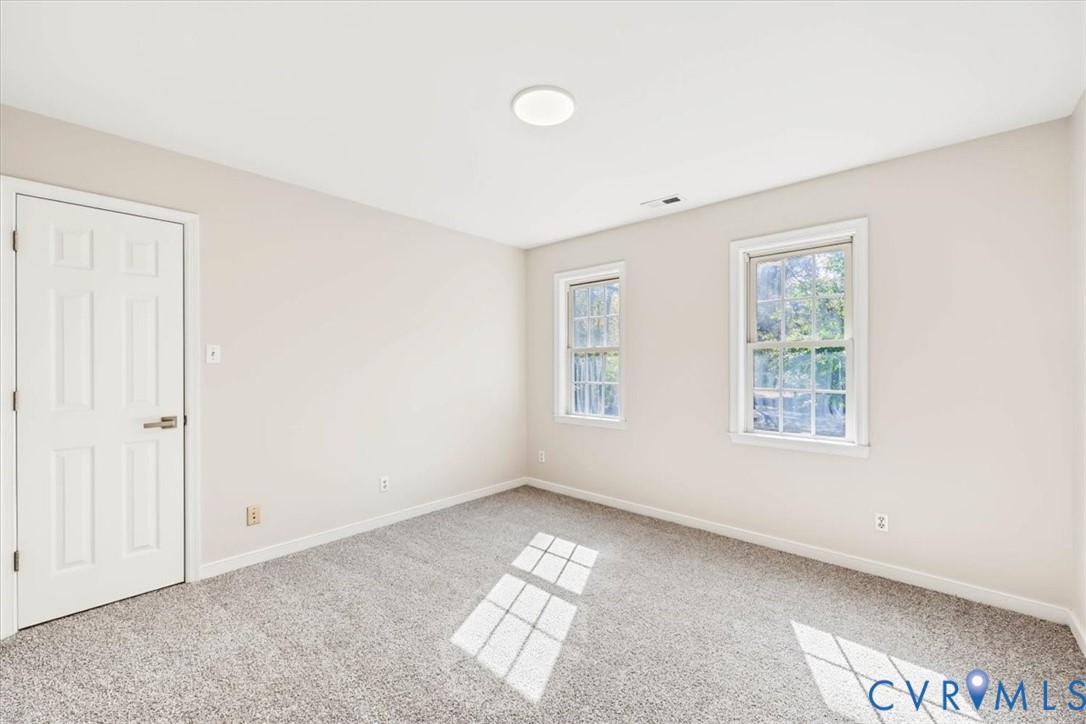 Neutral interior featuring wall-to-wall carpeting, two double-hung windows, and a six-panel interior door