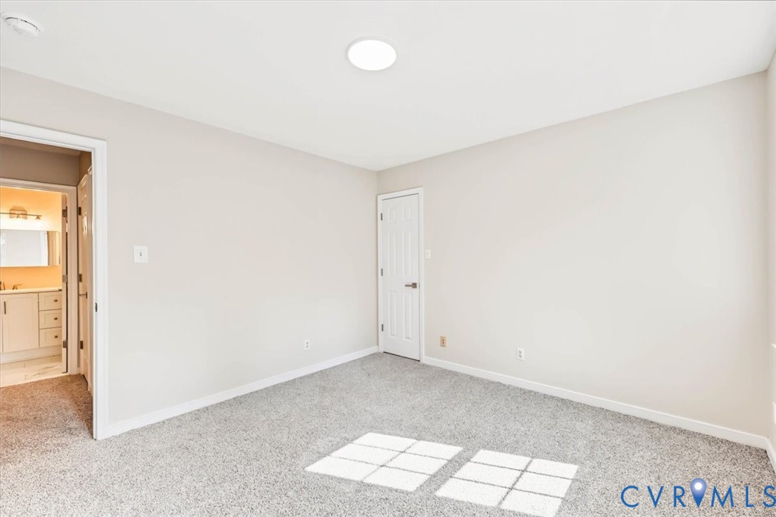 Neutral-toned interior space featuring neutral carpeting, a flush-mount ceiling light fixture, and a white six-panel interior door