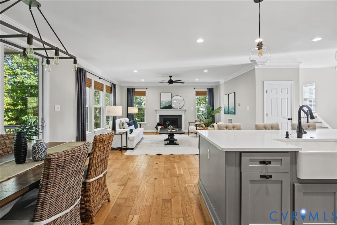 Open-concept living space featuring hardwood flooring, a gas fireplace with a dark mantel, and abundant natural light from large multi-pane windows