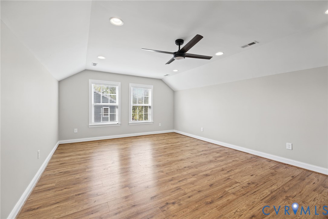 Vaulted ceilings featuring recessed lighting, wood-finish flooring, and a central matte black ceiling fan
