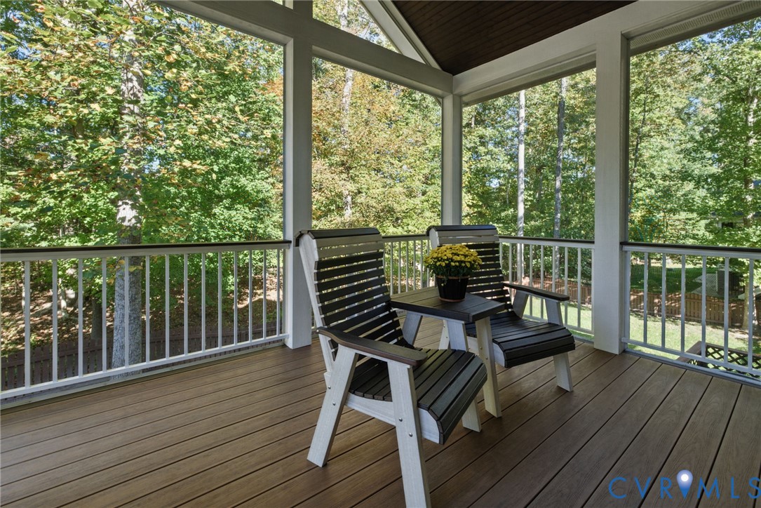 Screened-in porch featuring wood-finish decking, a vaulted ceiling, and white vertical baluster railings