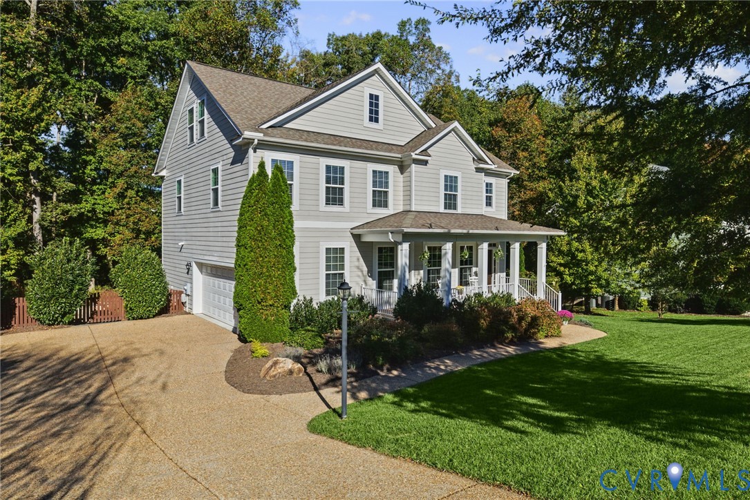 Two-story home with light-toned horizontal siding, gable roof lines, a covered front porch with columns, and an attached side-entry garage