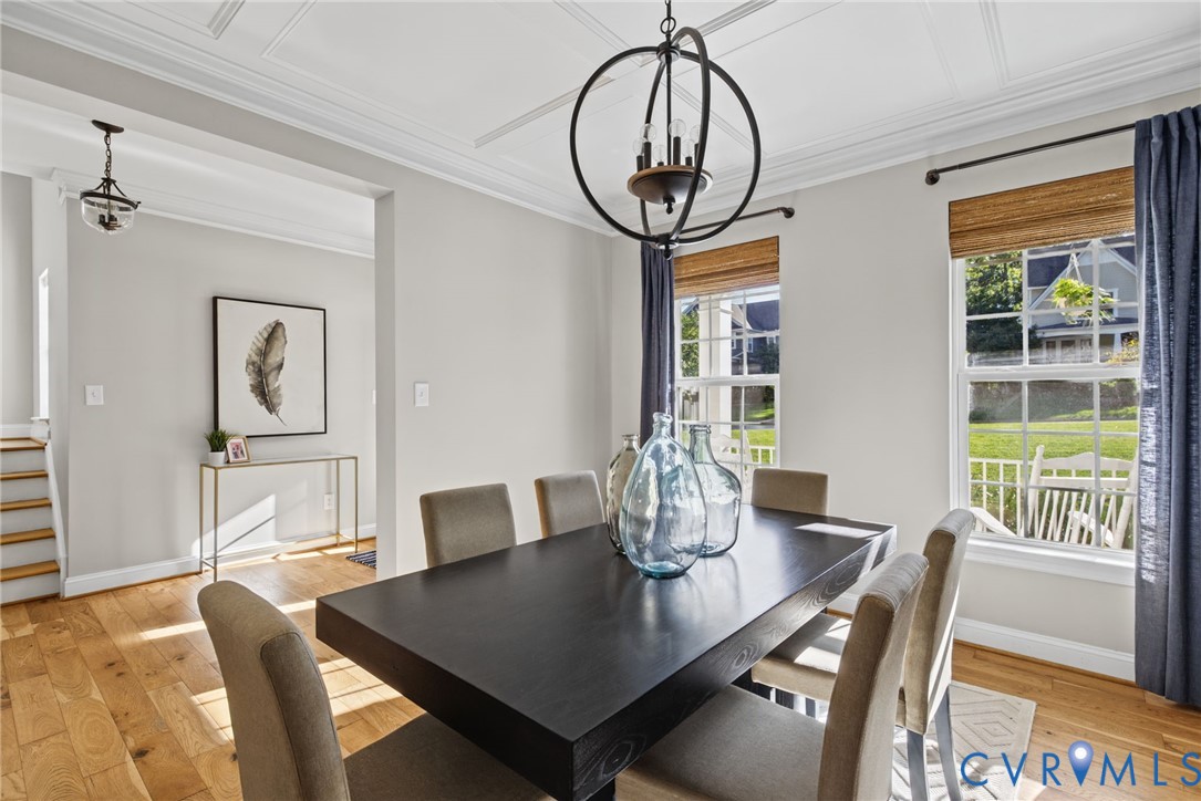 Dining room featuring wood-finish flooring, coffered ceiling detail, and a prominent spherical chandelier