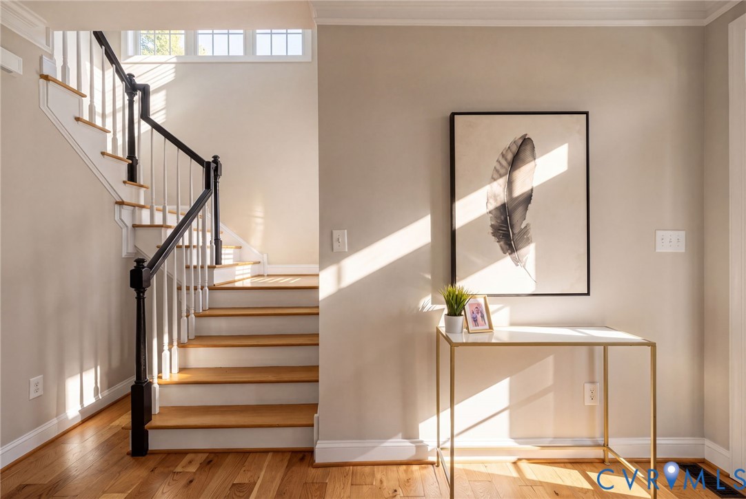 Staircase featuring wood-finish treads, white risers, a black-finished handrail, and white balusters, complemented by wood-finish flooring