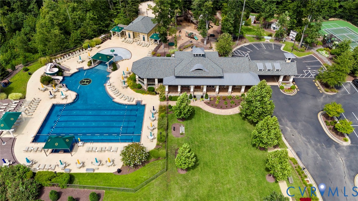 Community facility featuring an expansive outdoor swimming pool, dedicated tennis court, paved parking area, and manicured grounds