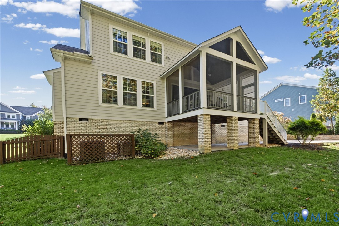 Rear exterior featuring horizontal lap siding, a brick foundation, a screened porch with a gable roof, and a wooden privacy lattice