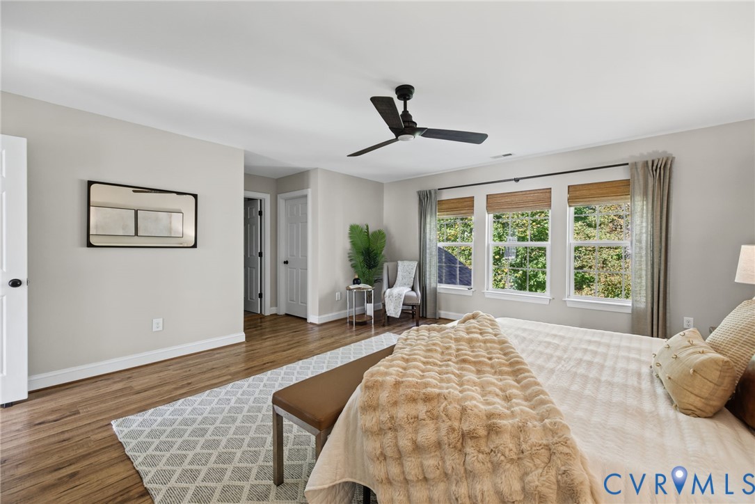 Neutral wall tones, wood-finish flooring, trio of windows, and matte black ceiling fan