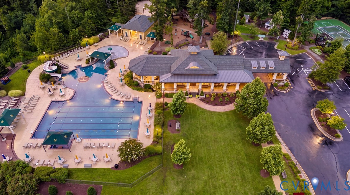 Community clubhouse featuring a multi-lane swimming pool, water slide, tennis court, and dedicated parking area