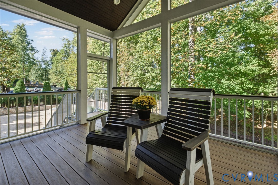 Screened porch featuring wood-finish decking, white railings, vaulted ceiling, and floor-to-ceiling windows