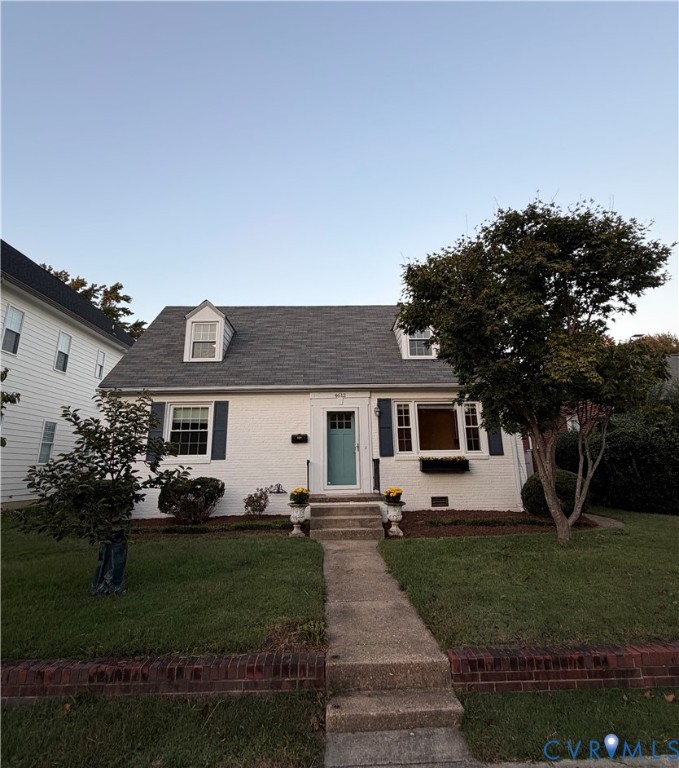 Cape Cod exterior featuring painted brick siding, dual dormer windows, shuttered multi-pane windows, and a central entryway with concrete steps Cape Cod exterior featuring painted brick siding, dual dormer windows, shuttered multi-pane windows, and a central entryway with concrete steps